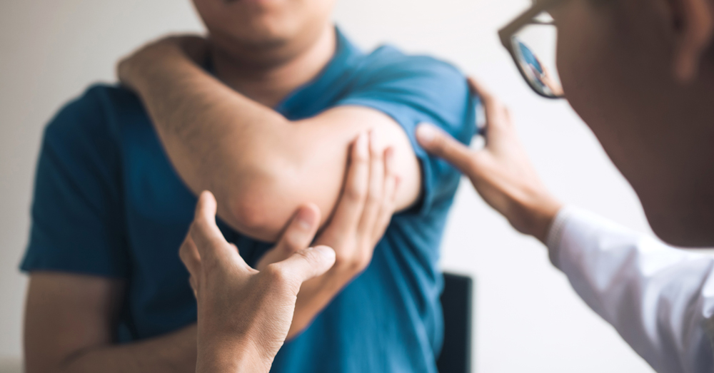doctor examining a man's injured elbow after discussing his options first with a personal injury attorney