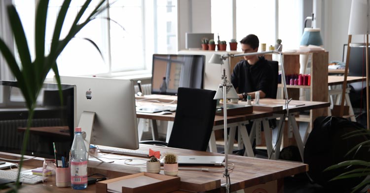 alone coworker at computer desk in office after business owner opens back up